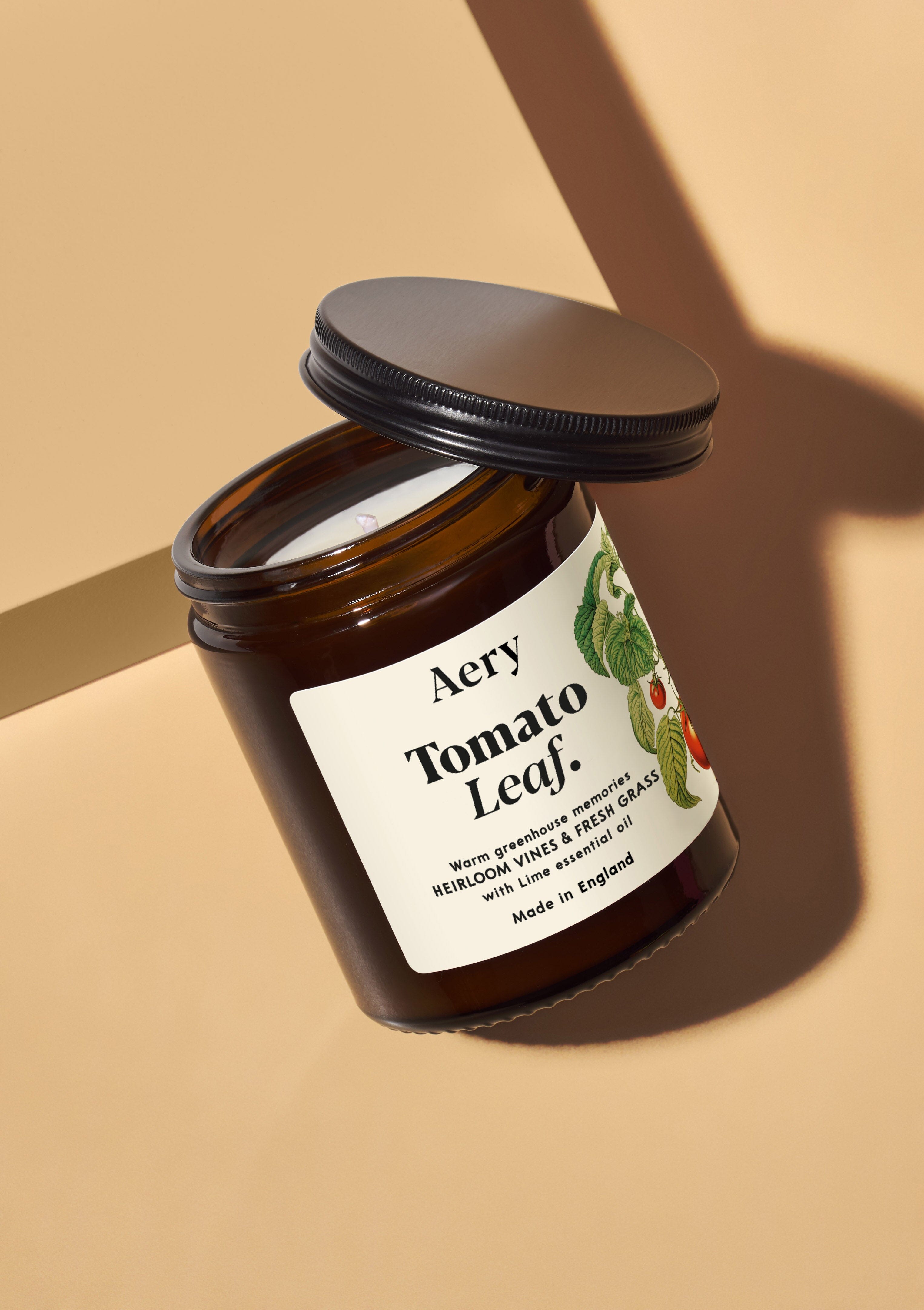 tomato leaf amber glass jar candle with decorative label on coloured background
