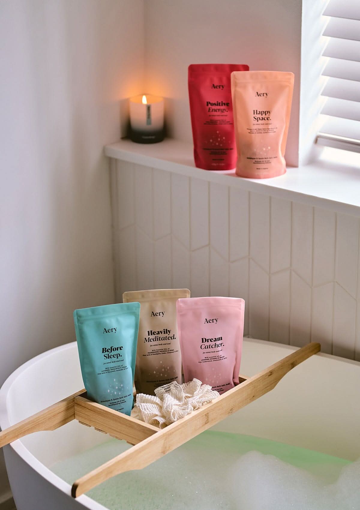 Collection of Aromatherapy bath salts pouches by Aery displayed in bathroom with bathtub