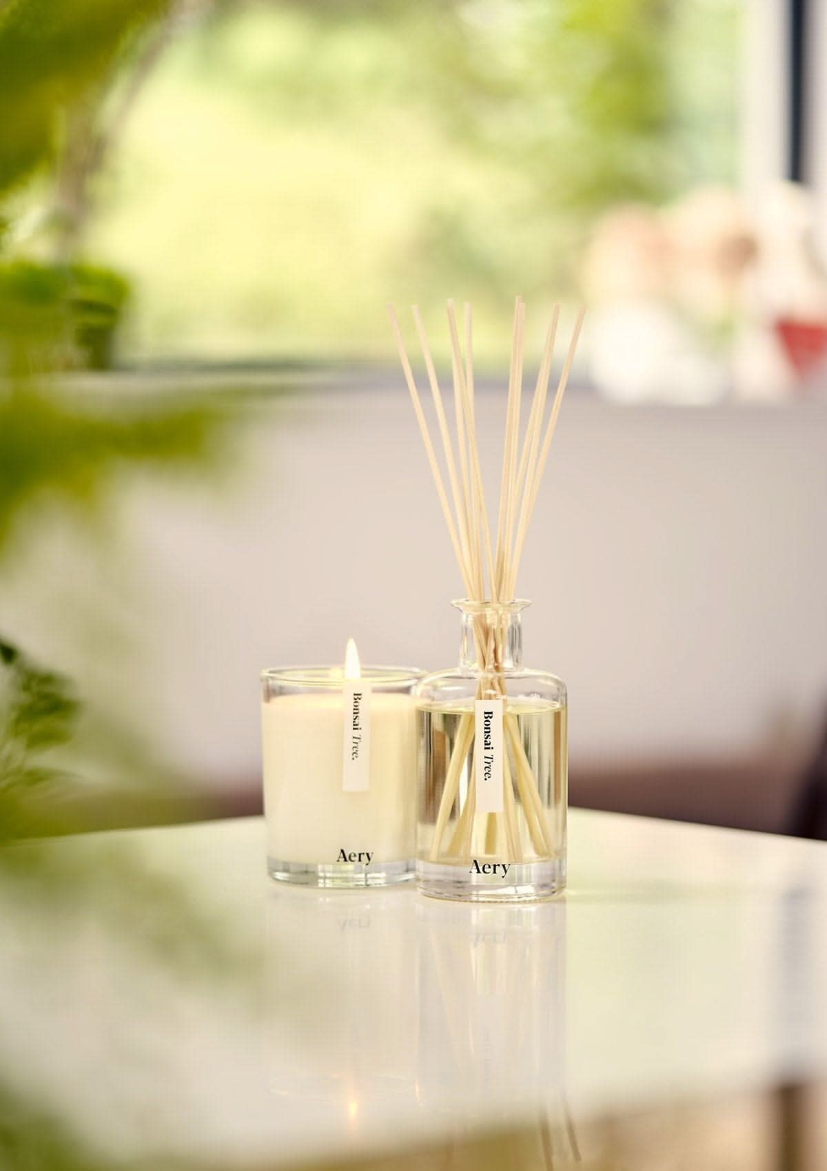 Cream Bonsai Tree diffuser by Aery displayed next to bonsai tree candle placed on kitchen worktop