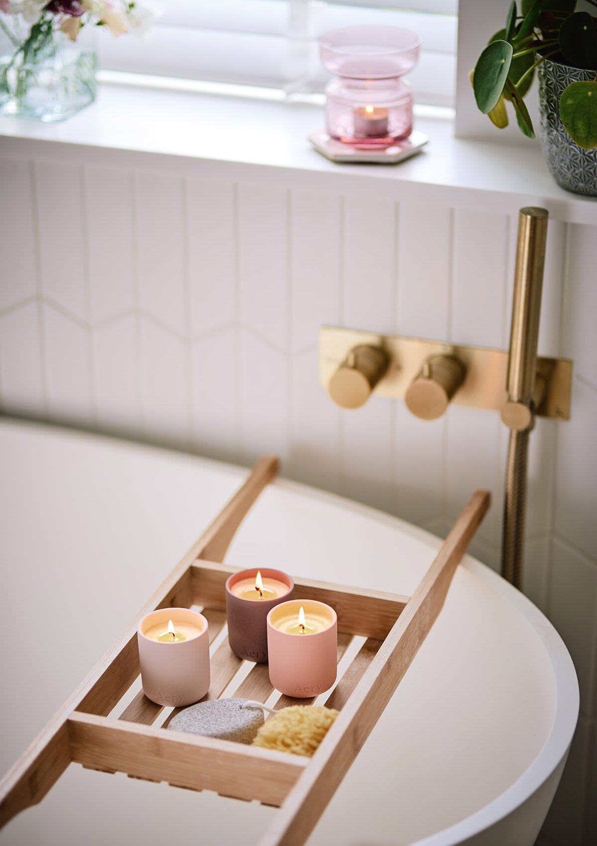 Pink Wanderlust set of three candles by Aery  placed on wooden bath tray in bathroom