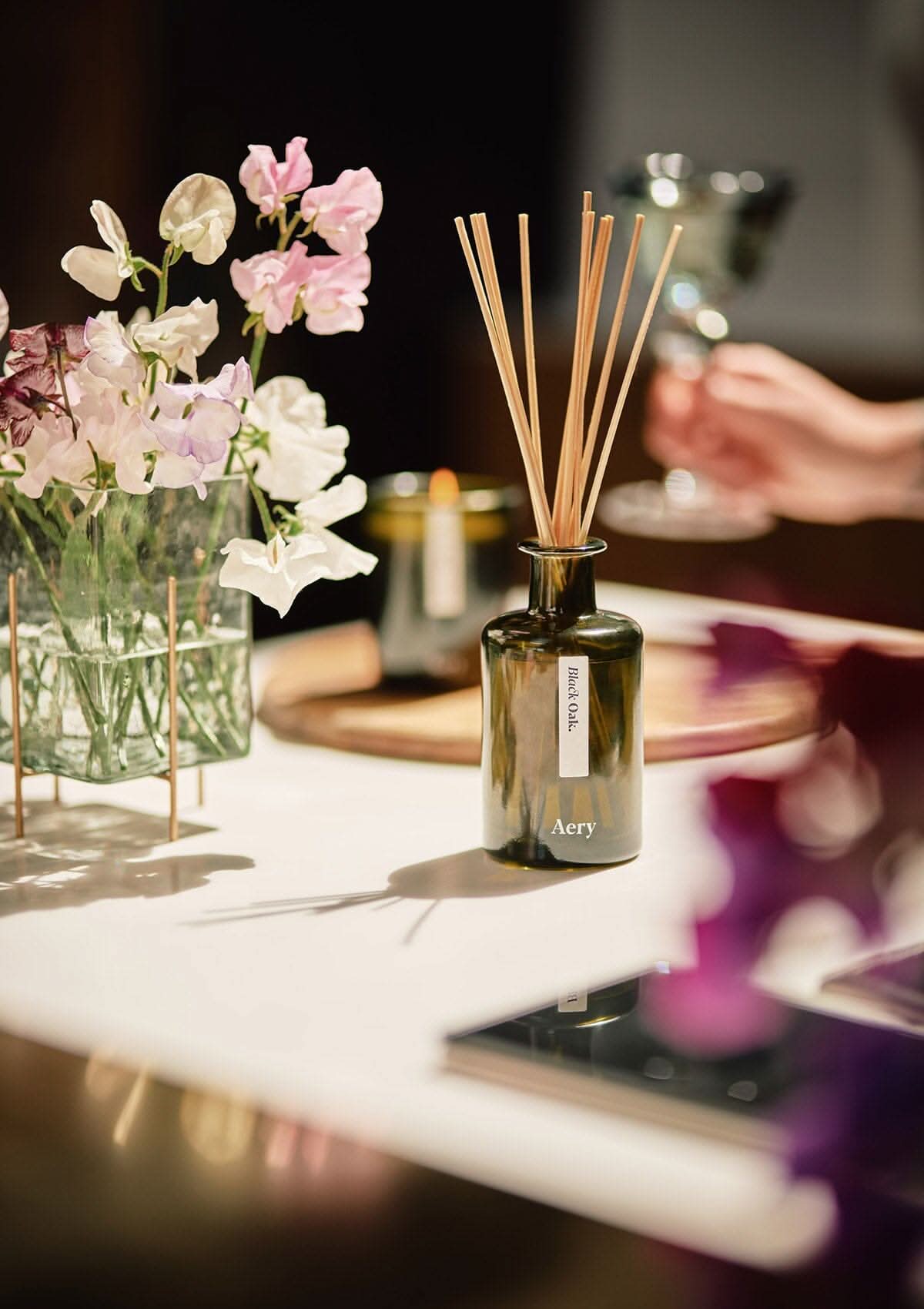Green Black Oak diffuser by Aery displayed with vase of flowers on kitchen worktop