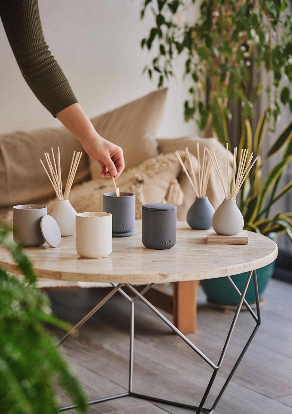 Collection of Fernweh diffusers and candles by Aery displayed on round cream table in kitchen