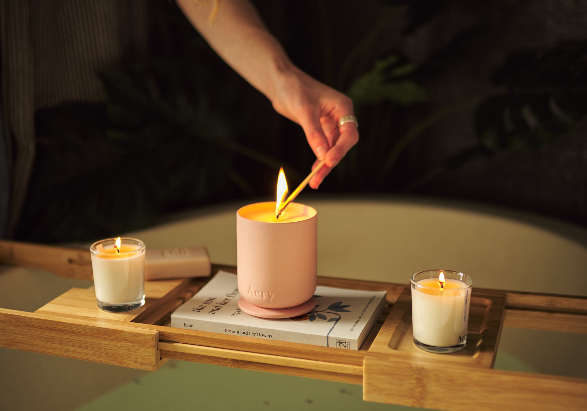bath caddy with three lit candles and book