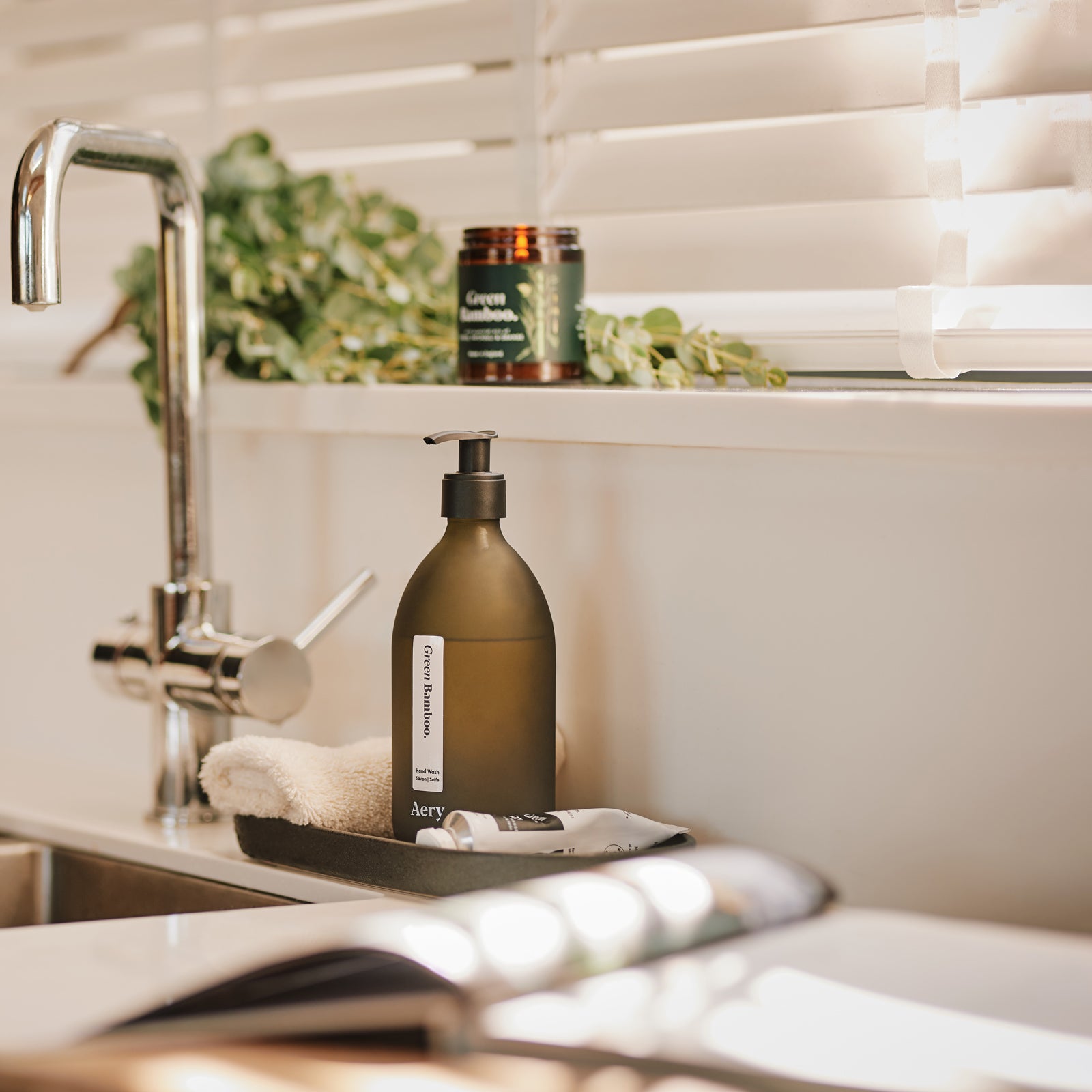 Kitchen sink setting with green bamboo aery living candle, hand wash and hand cream