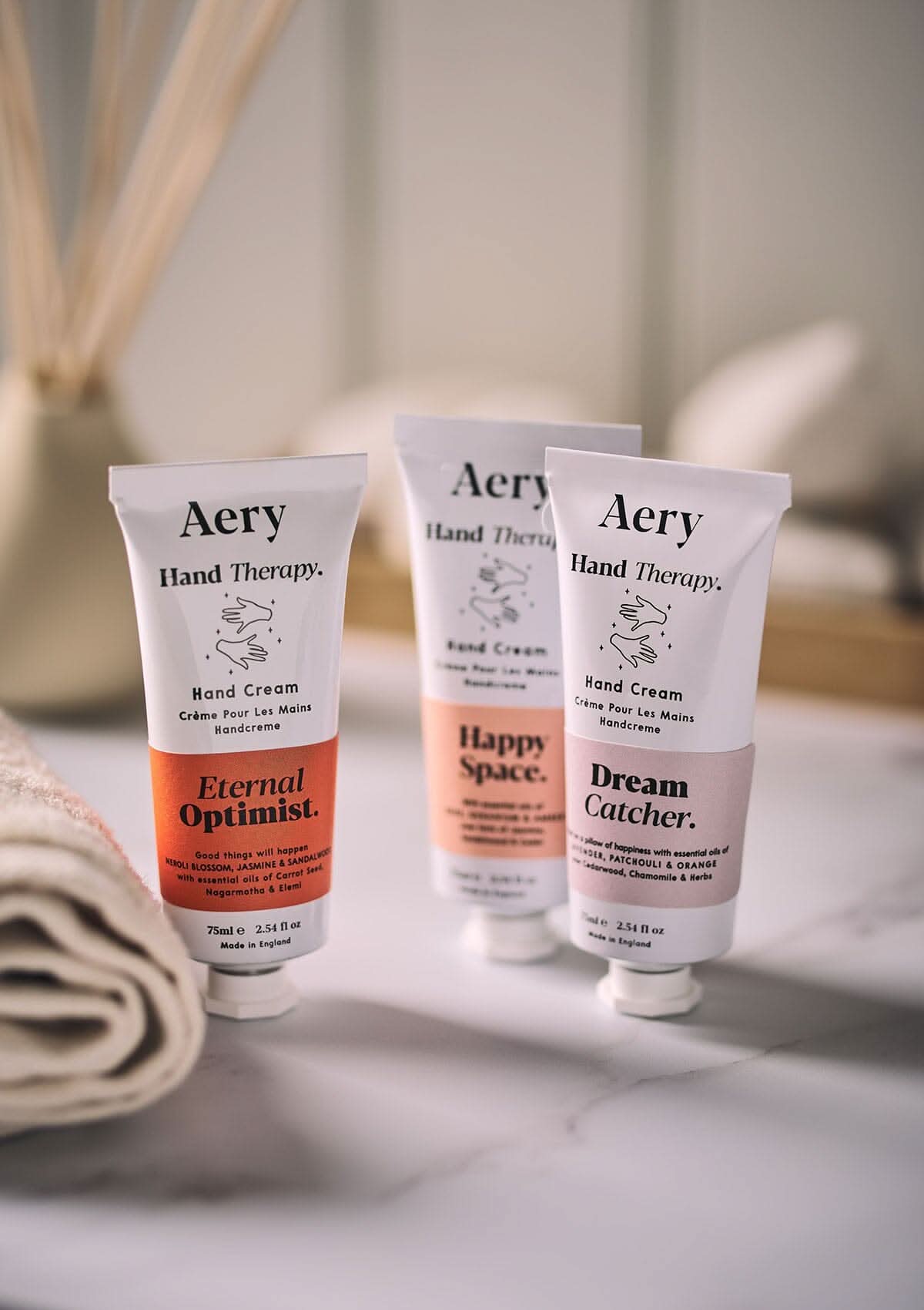 Orange Eternal Optimist hand cream by Aery displayed next to Dream Catcher and Happy Space hand cream on bathroom surface