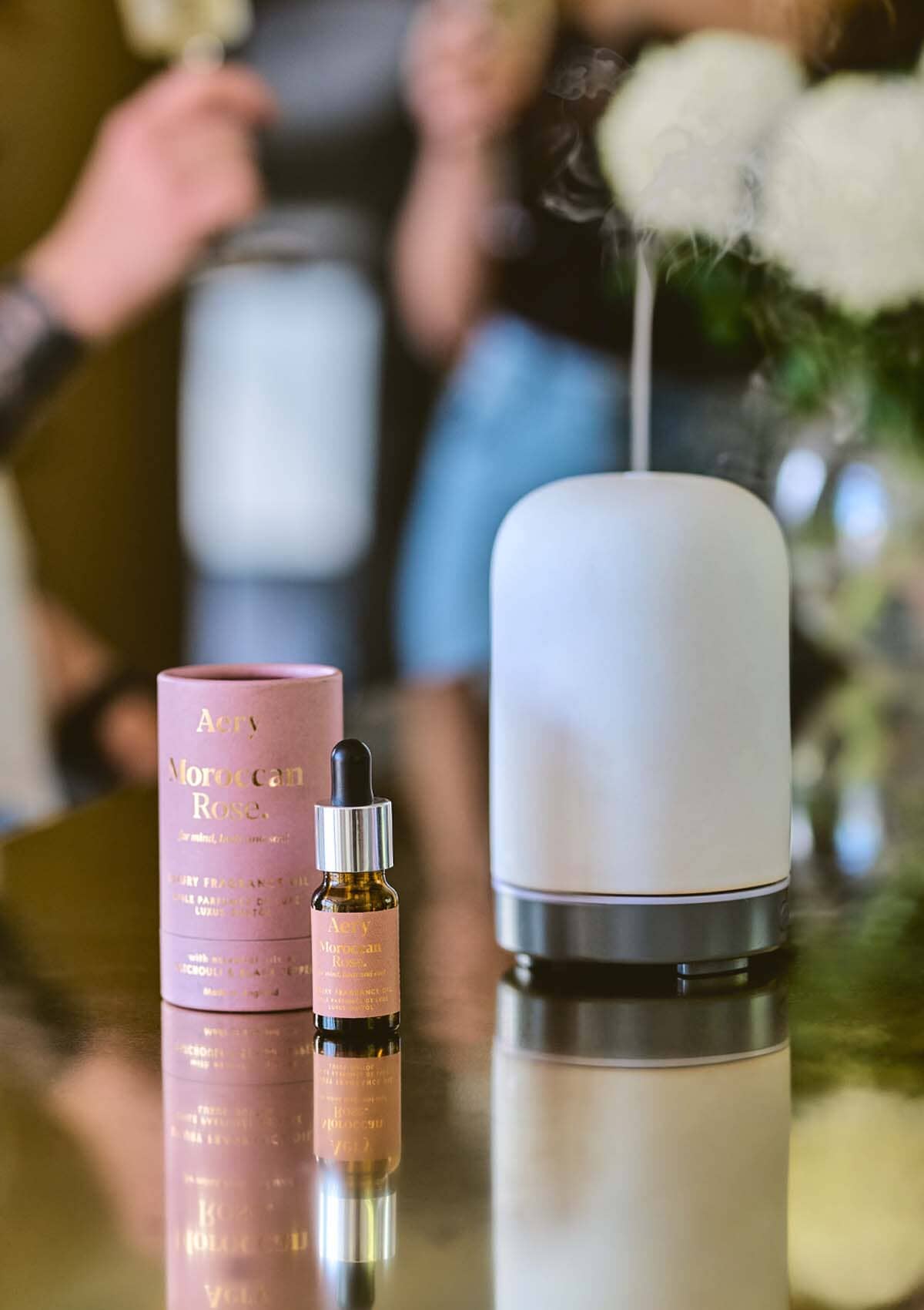 Moroccan Rose fragrance oil displayed next to product packaging on gold surface 