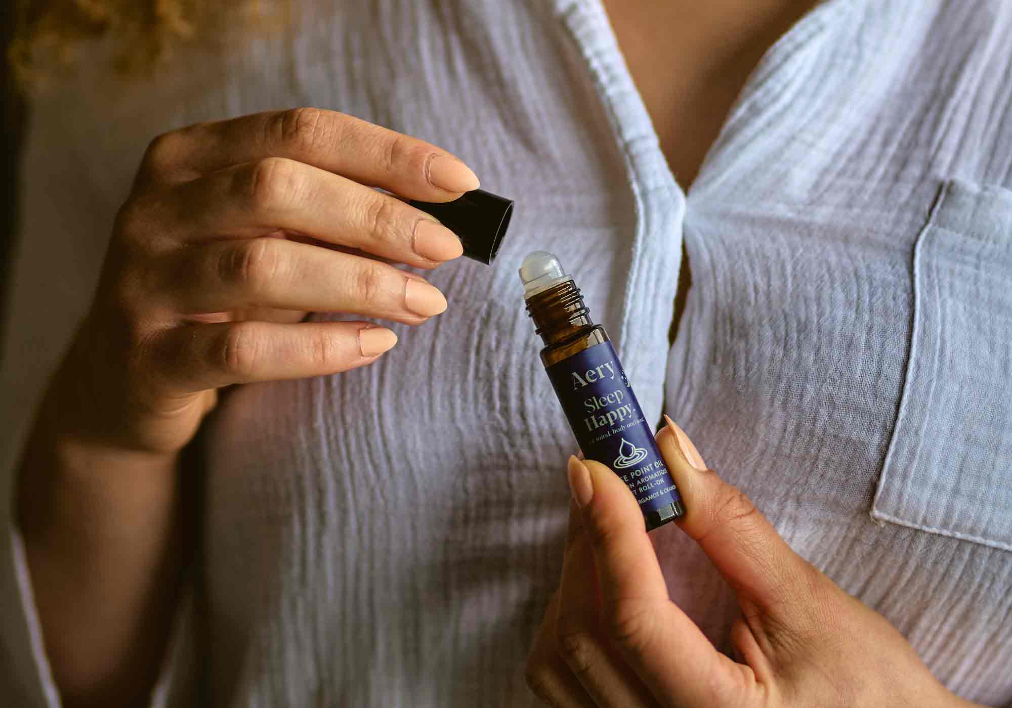 person holding pulse point roller ball in sleep happy fragrance in pyjamas 