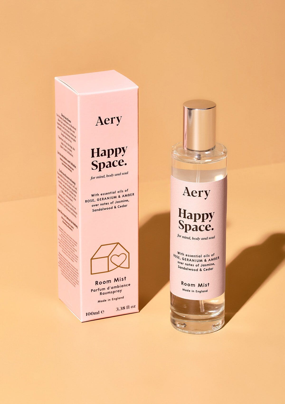pink bottle of happy space room mist displayed next to product packaging