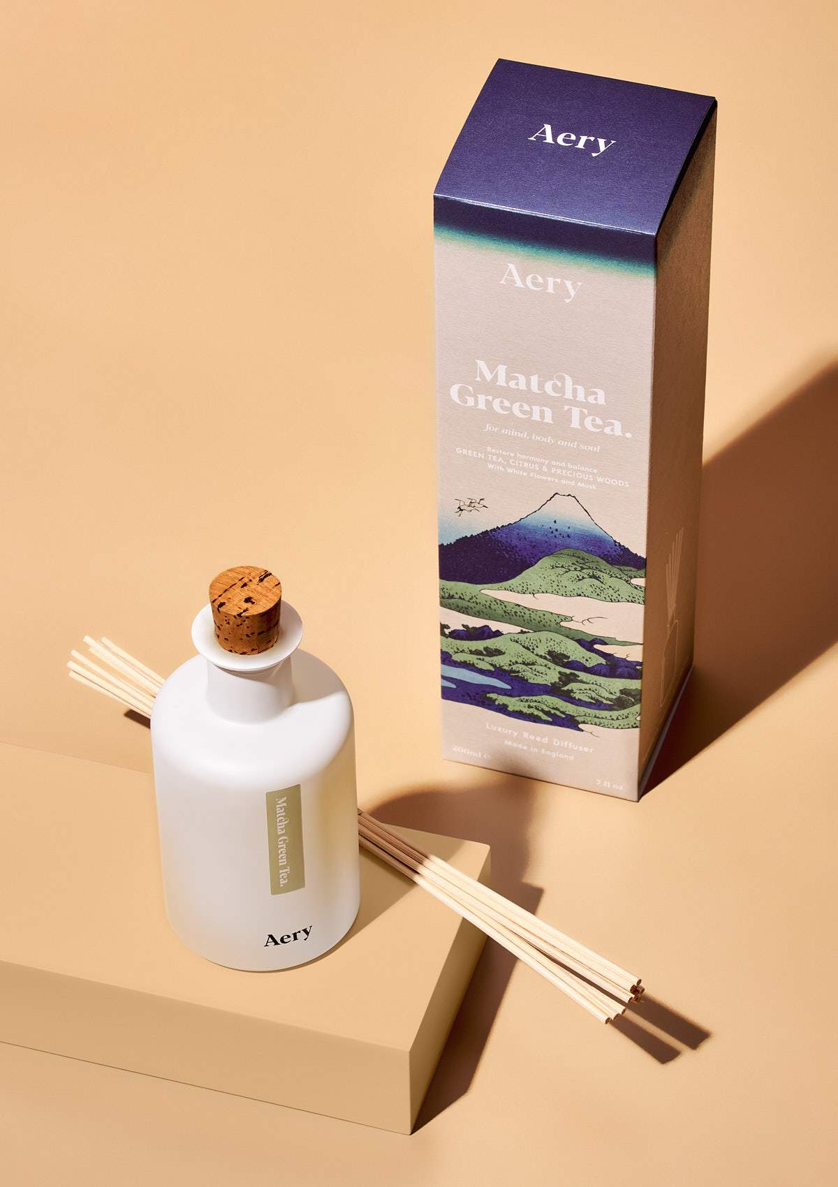 aery living matcha green tea reed diffuser next to product packaging on an orange background