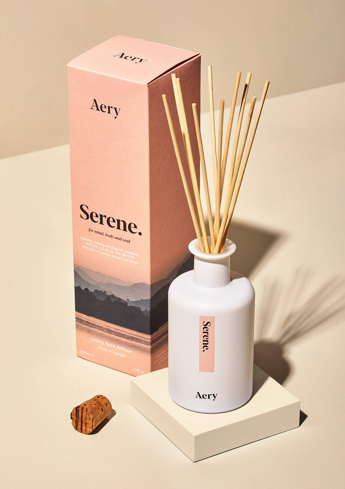 aery living reed diffuser next to pink product packaging on a cream background
