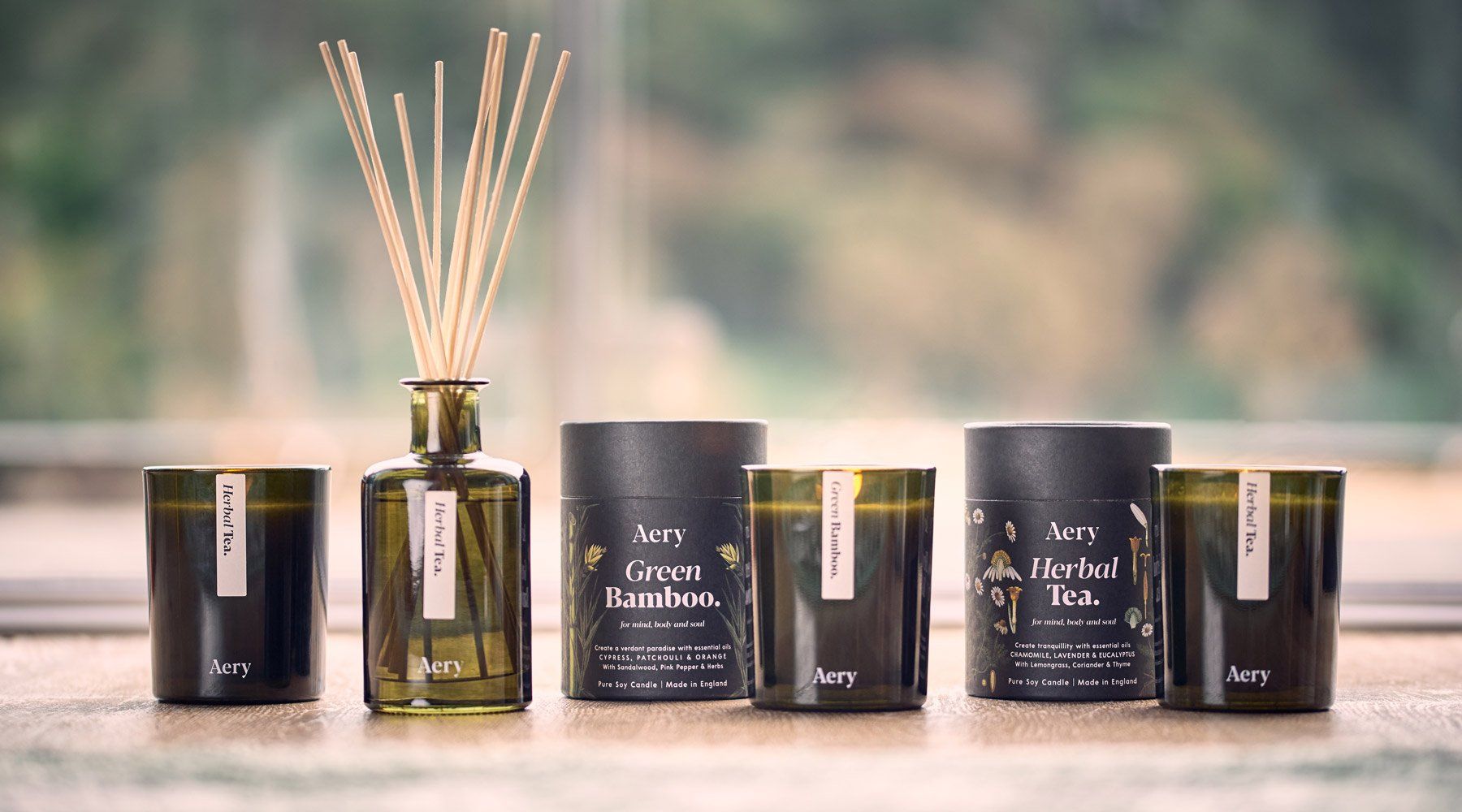 aery green botanical candles and packaging with matching green bottle reed diffuser