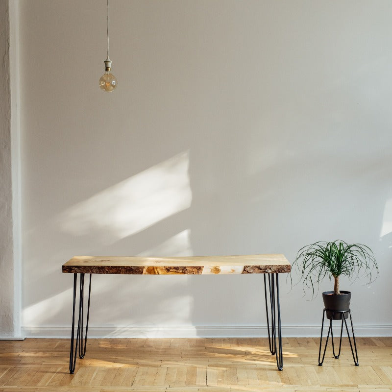 Table in front of a white wall and on top of an oak floor next to a potted plant