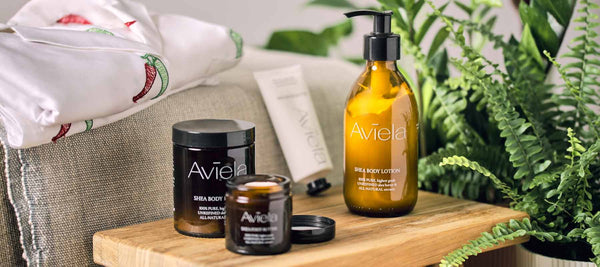aviela skincare products displayed on top of a stool with folded pijamas and house plants in the background