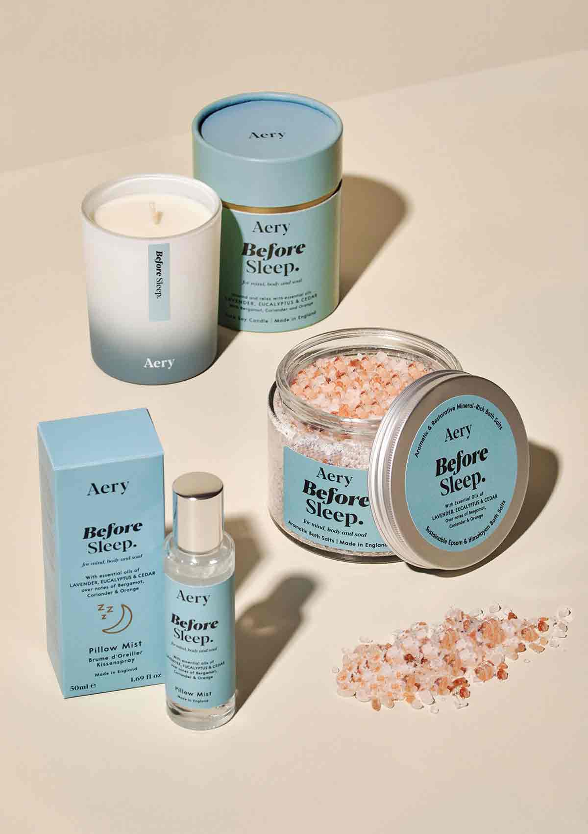 A collection of before sleep candle, pillow mist and bath salts by aery displayed with product packaging on cream background 
