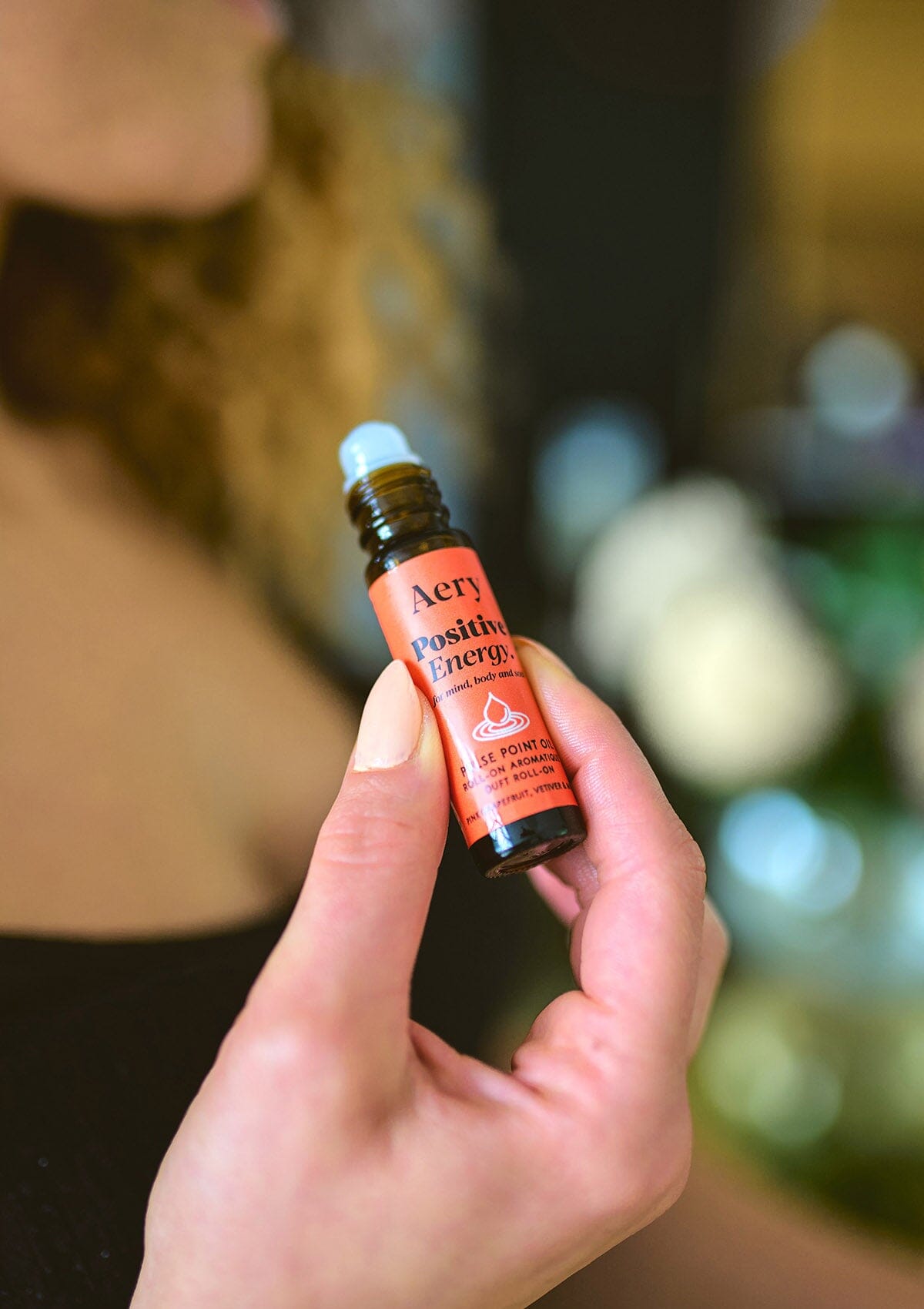 Red Positive Energy pulse point oil by Aery displayed in hands