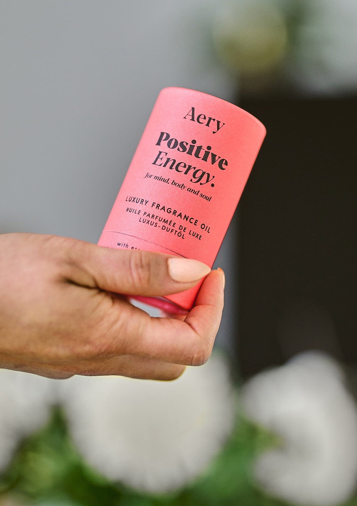 Red Positive Energy fragrance oil  product packaging by Aery displayed in hand 