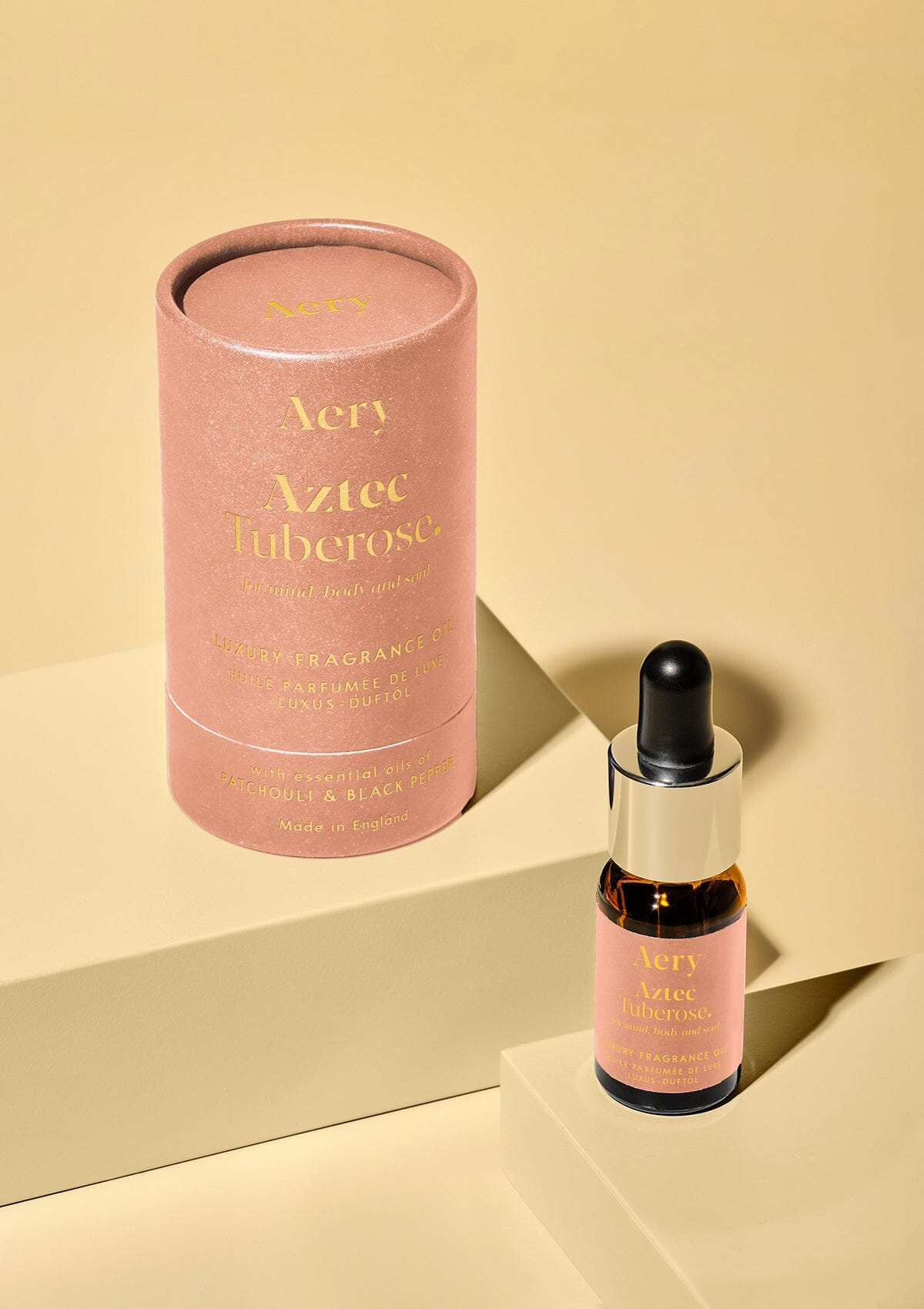 Pink Aztec Tuberose fragrance oil by aery displayed next to product packaging on yellow background 