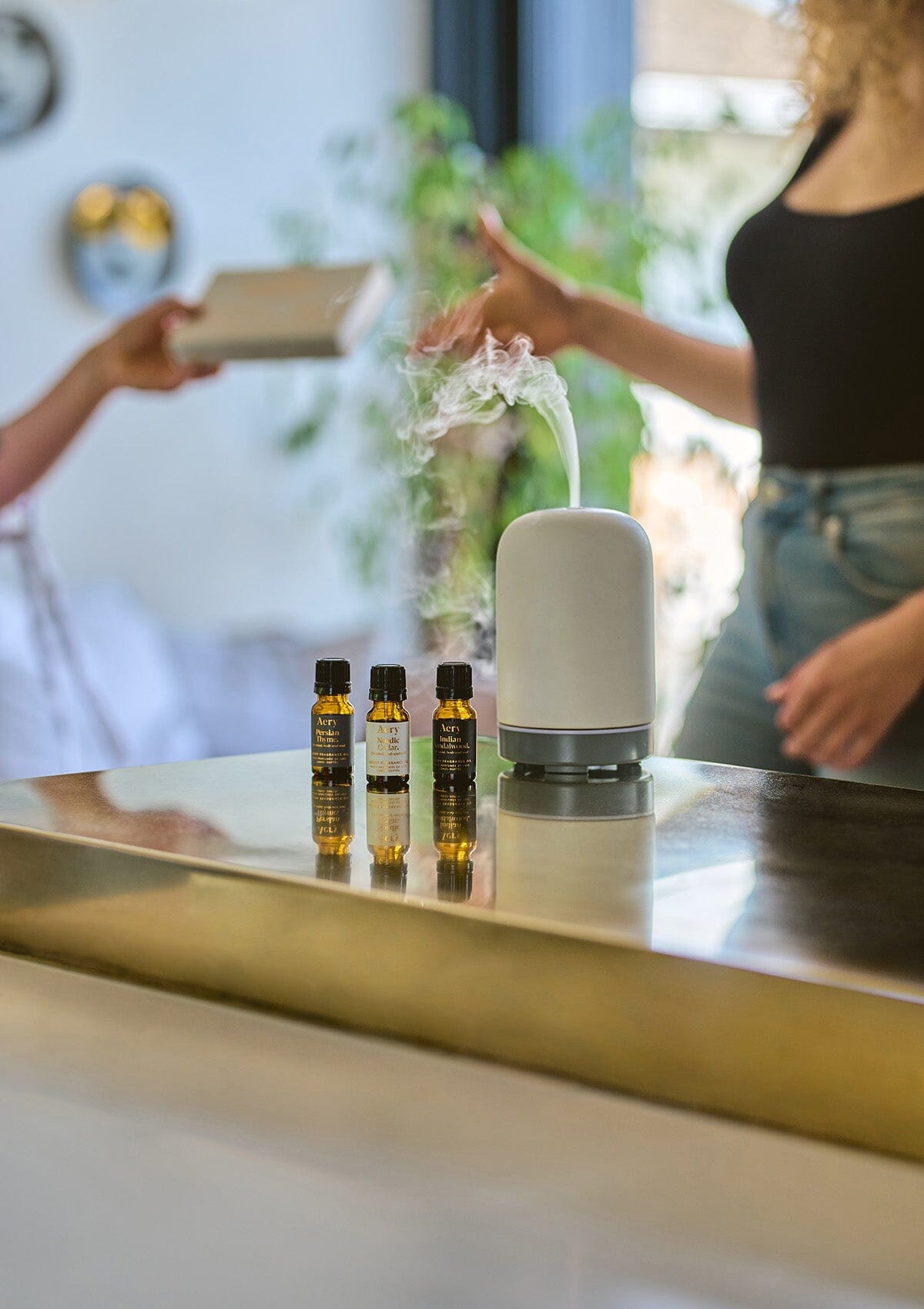 White Wonderland set of three fragrance oils displayed next to electric diffuser on gold kitchen worktop