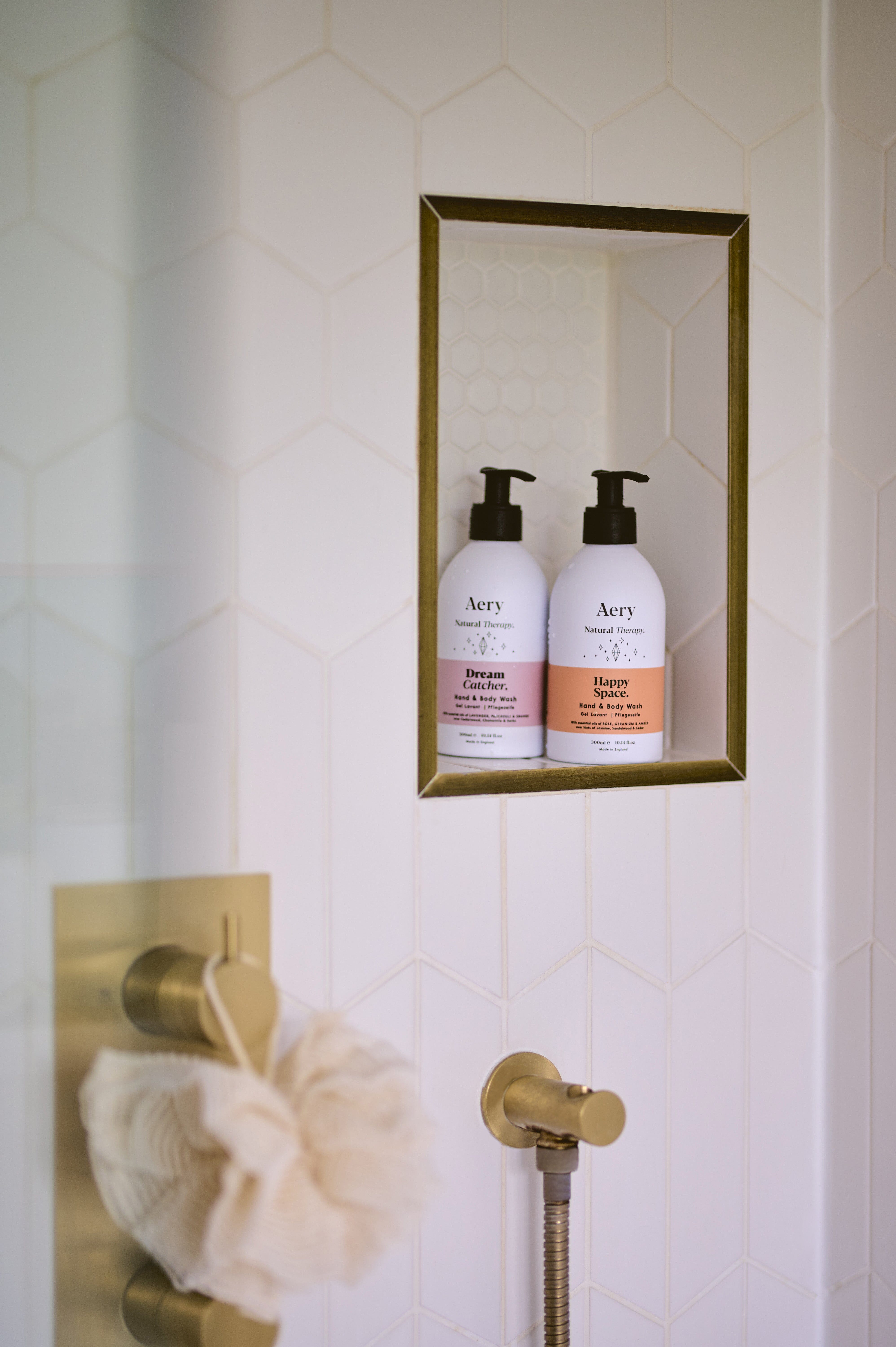 Lilac Dream Catcher hand wash by Aery displayed next to Pink Happy Space hand wash placed on shelf in shower 