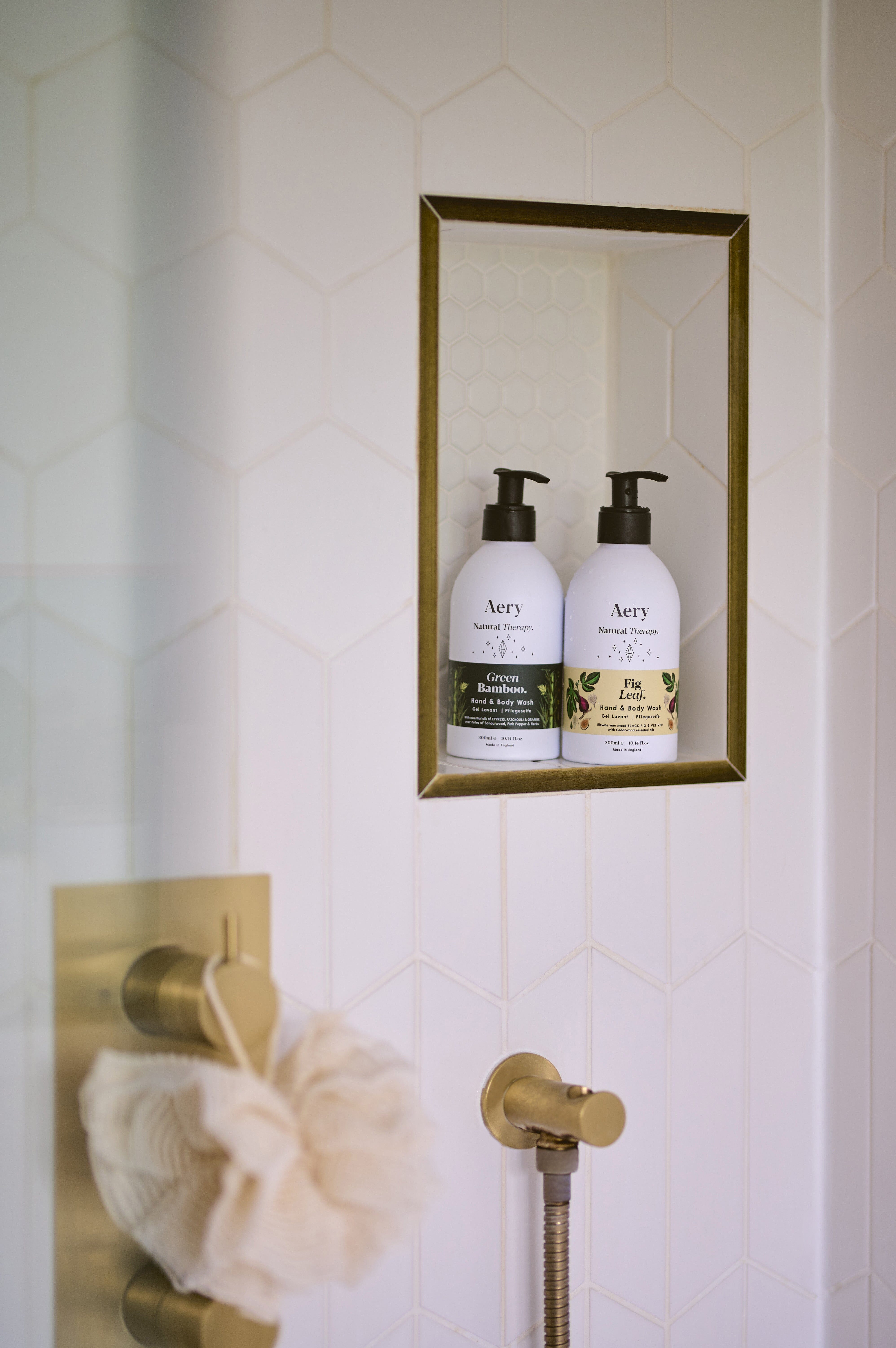 Cream Fig Leaf hand wash displayed next to Green Bamboo hand wash by Aery placed on shelf in shower 