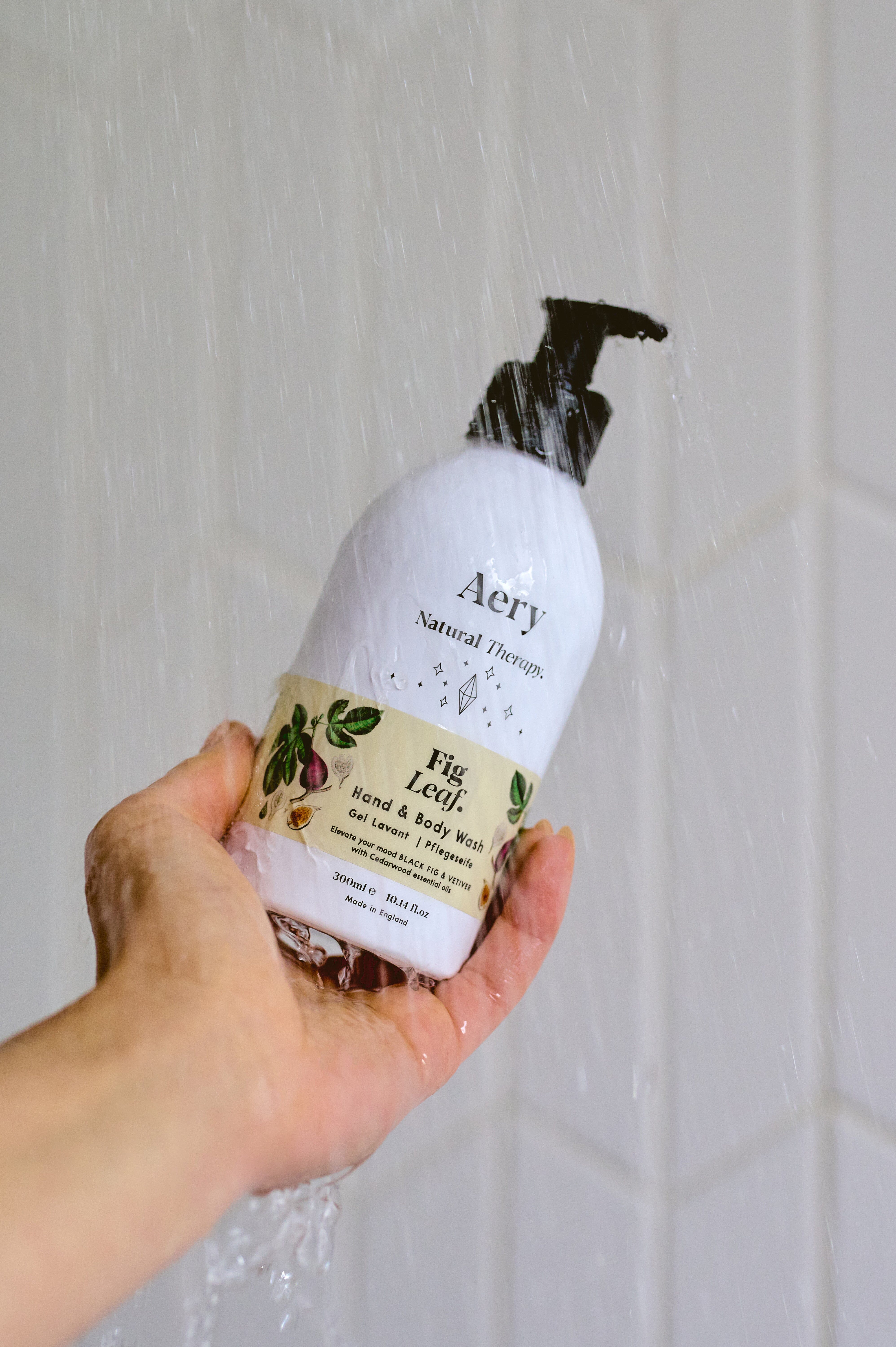 Cream Fig Leaf hand and body wash by Aery displayed in hand in shower 
