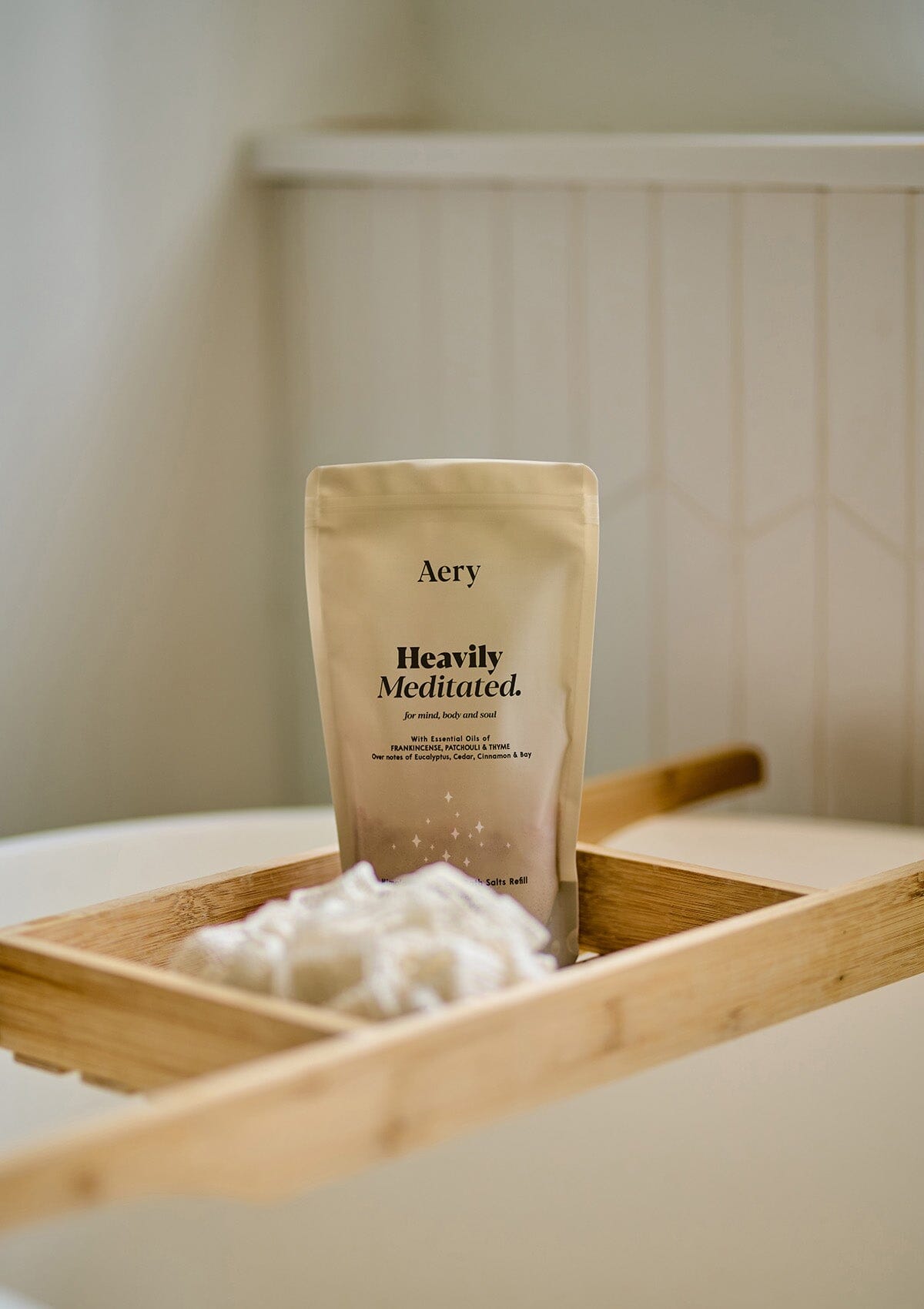 Beige Heavily Mediated bath salts pouch by Aery displayed on wooden bath tray in bathroom 