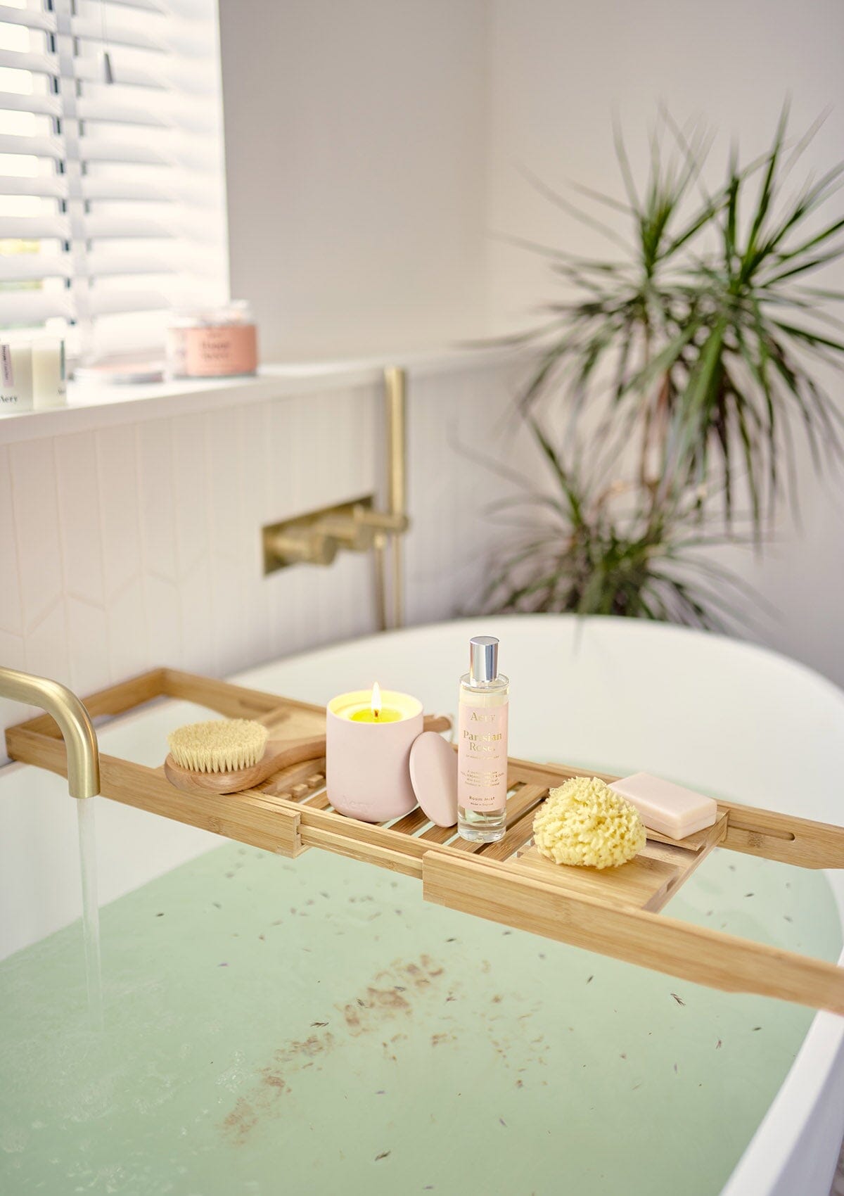 Pale Pink Parisian Rose room mist by Aery displayed next to Parisian Rose candle on wooden bath tray in bathroom 
