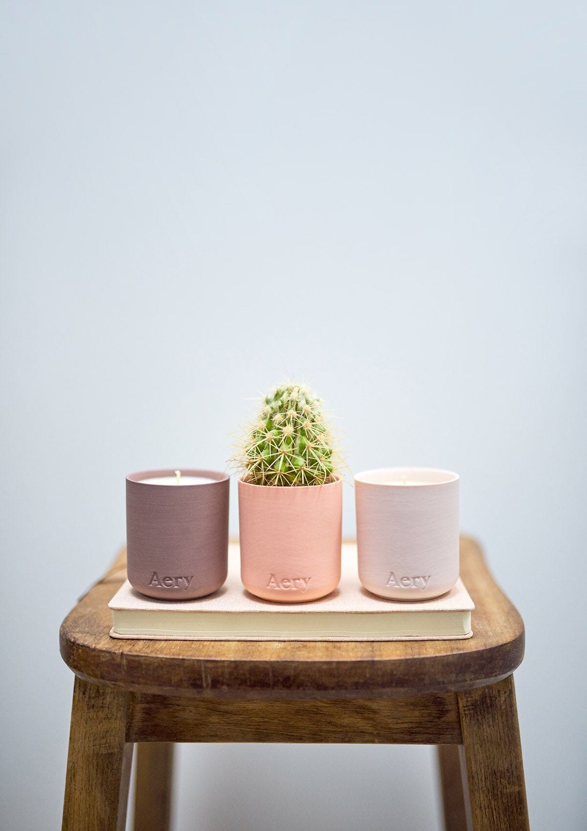 Pink Wanderlust set of three candles by Aery placed in a row on wooded stool 