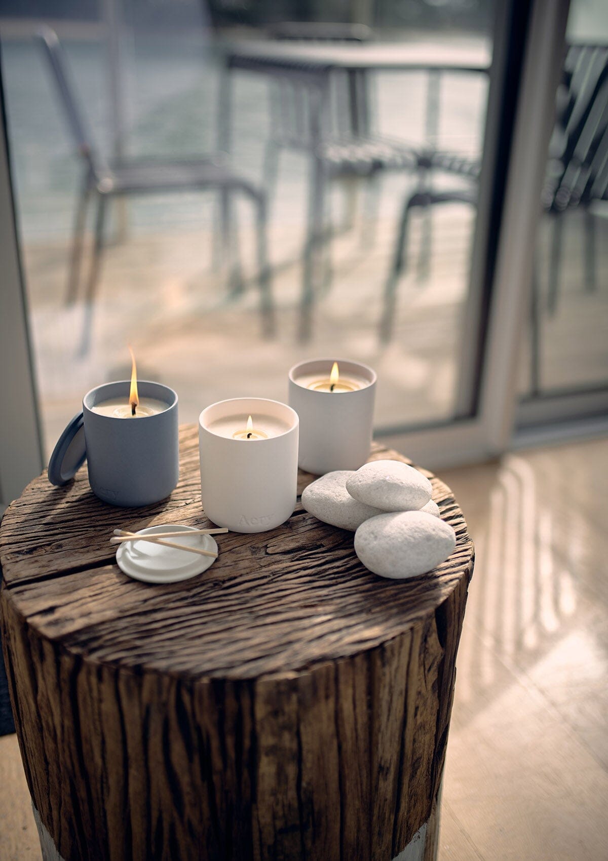 Wonderland set of three candles by Aery displayed  on wooden stall with grey pebbles 