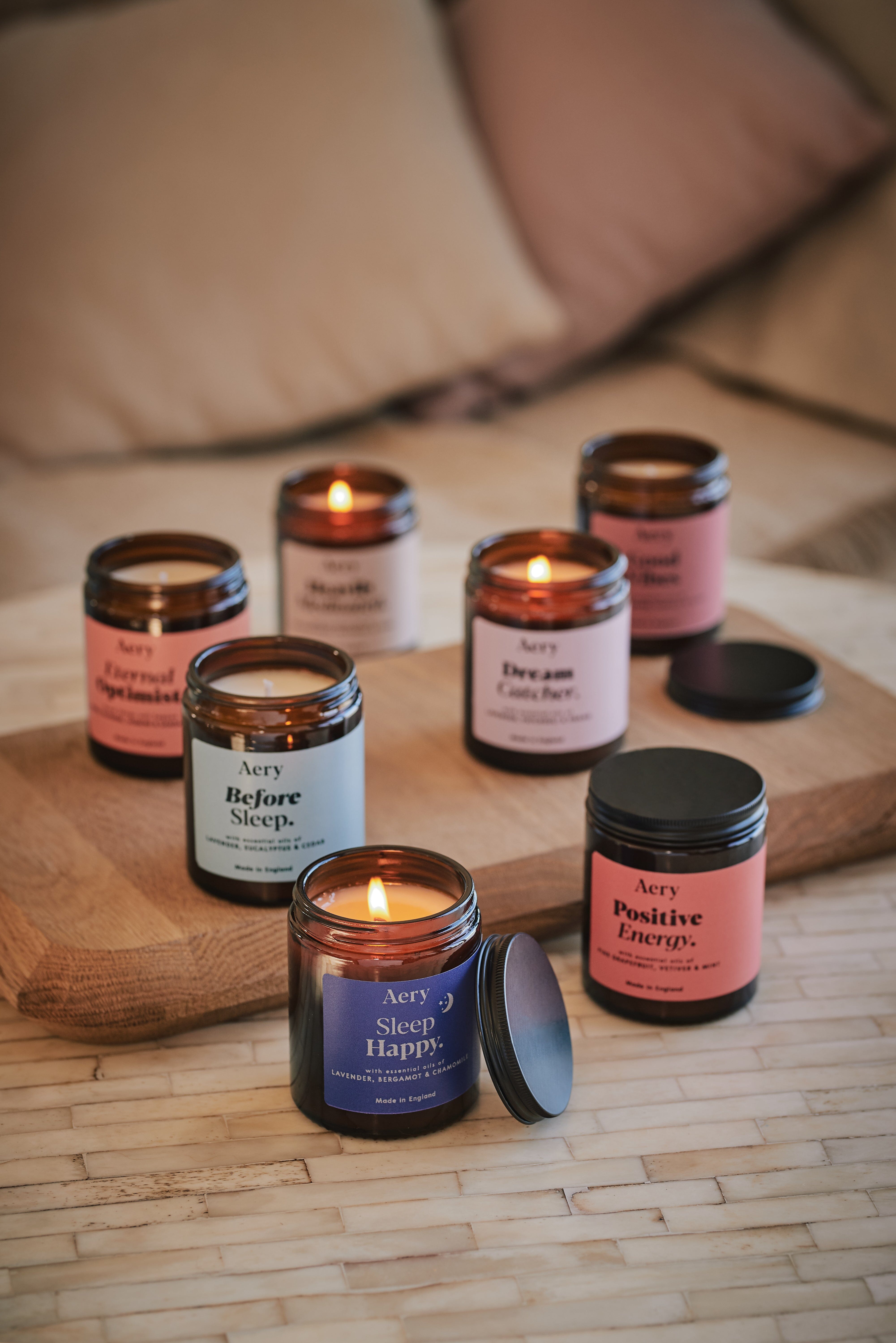 Collection of Aromatherapy jar candles by Aery displayed on wooden tray and and cream table 