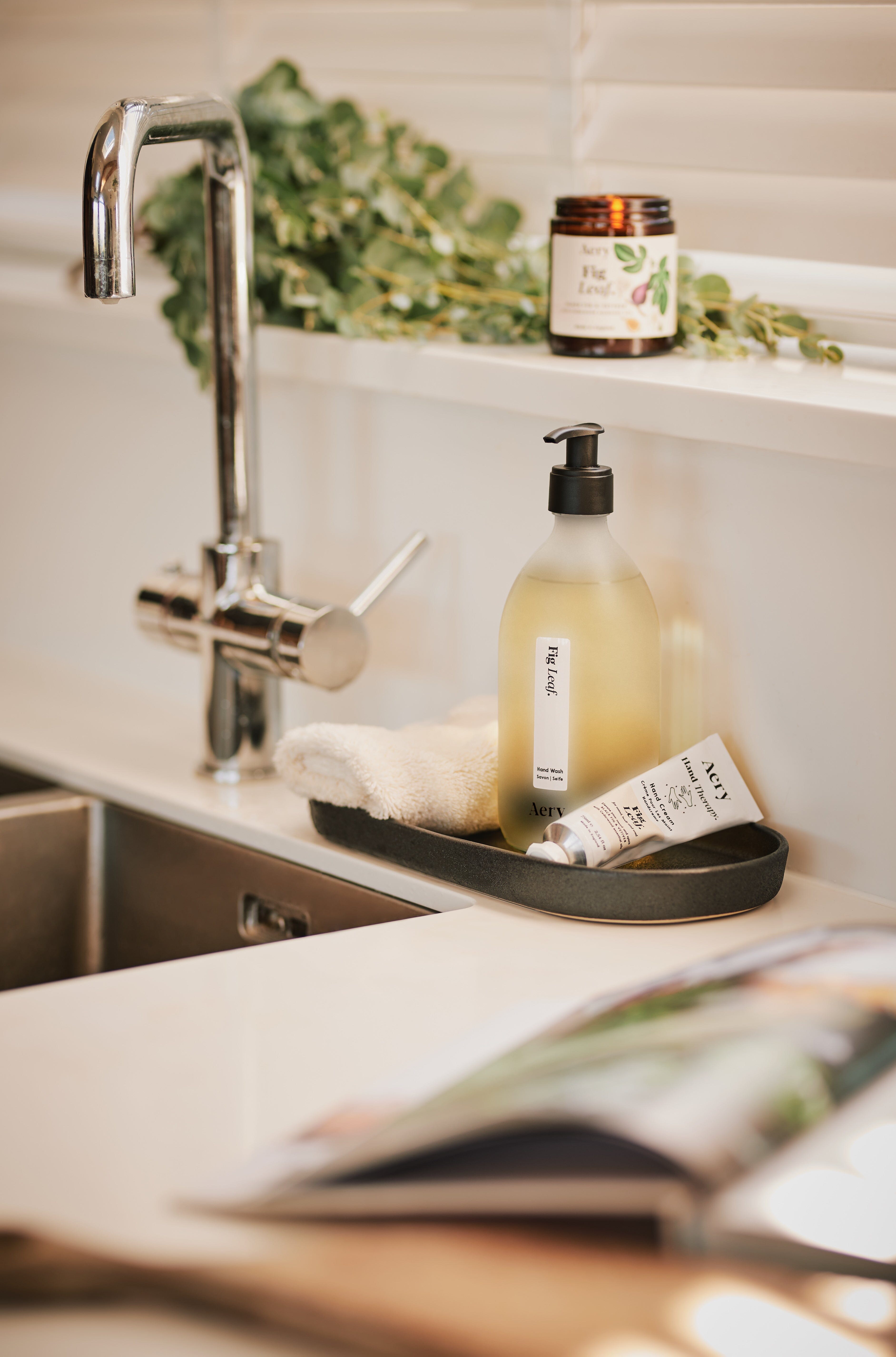 Cream Fig Leaf hand wash displayed next Fig Leaf hand cream and jar candle placed next to kitchen sink 