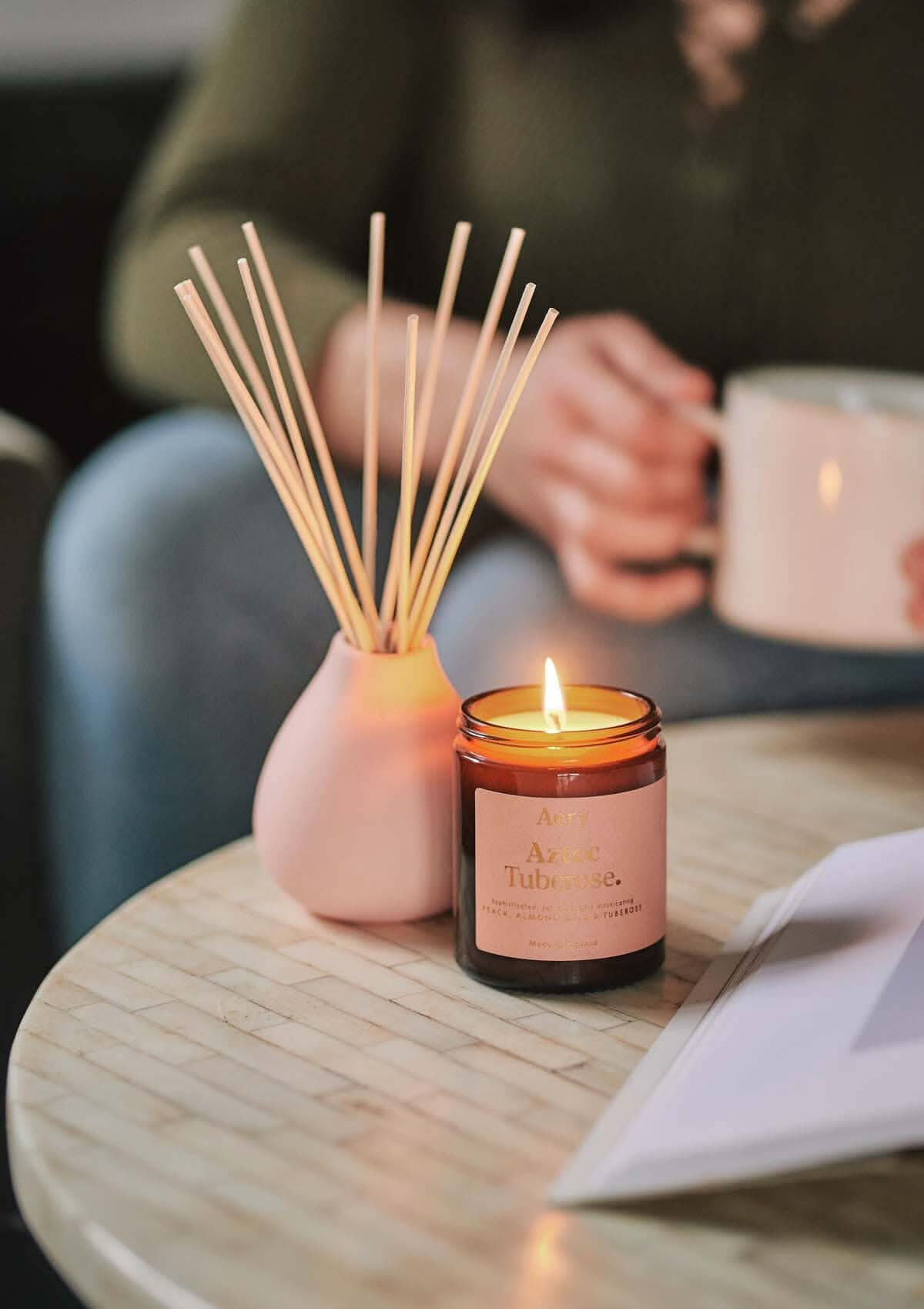 Pink Aztec tuberose jar candle by aery displayed next to aztec tuberose diffuser by aery placed on cream table