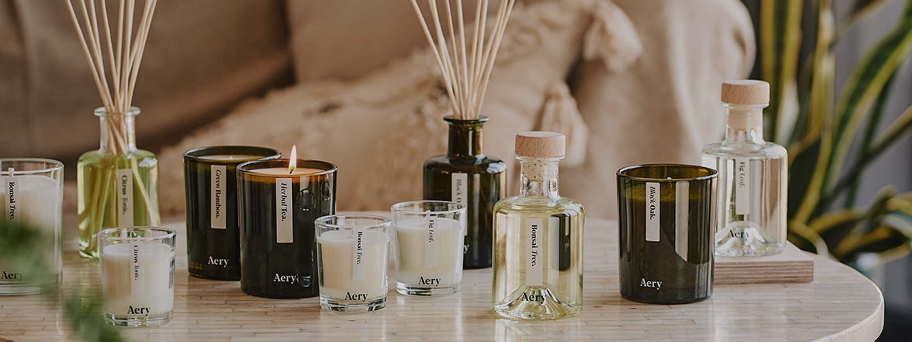 Green Botanical collection of diffusers and candles by Aery displayed on cream circle table 