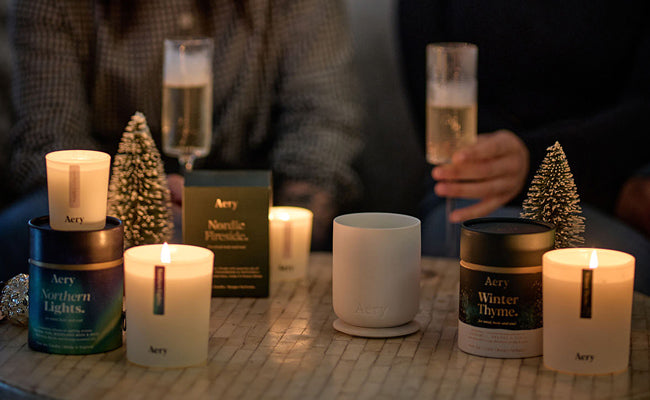 collection of aery christmas candles displayed in festive setting with people drinking in the background
