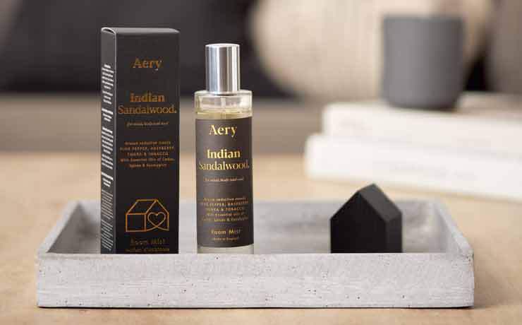 aery living black bottle and matching packaging for room mist displayed on a coffee table on top of a ceramic tray