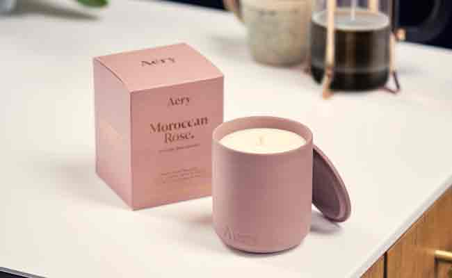 moroccan rose scented candle in dusty pink next to product packaging on a kitchen counter top with cafetiere in the background 