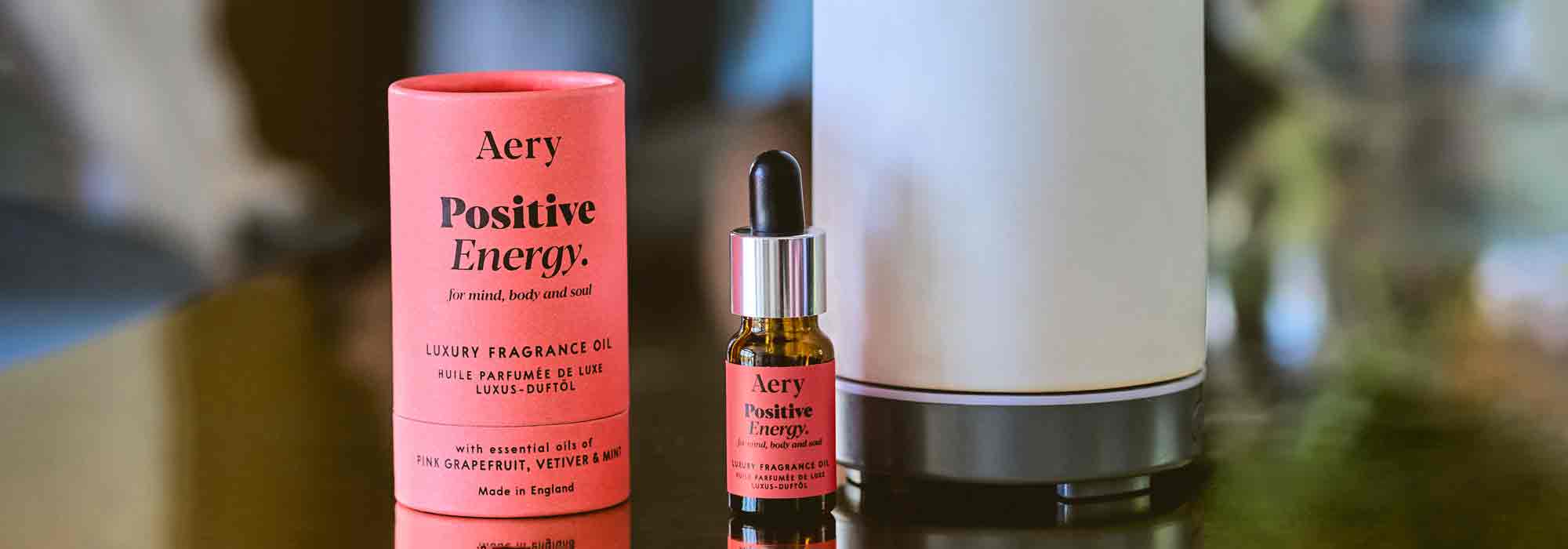 positive energy fragrance oil next to product packaging and air diffuser