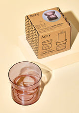 aery living glass tea light holder in dusky pink coloured glass displayed next to decorative product packaging against a cream background