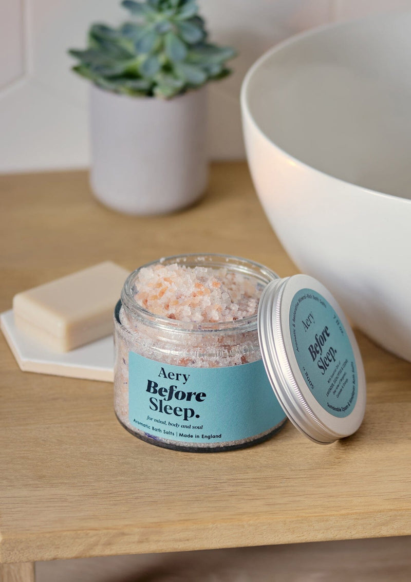 aery living before sleep bath salts displayed in bathroom setting next to sink with lid off