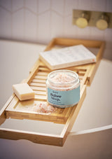 aery living before sleep bath salts displayed decoratively on bath caddy next to soap and book