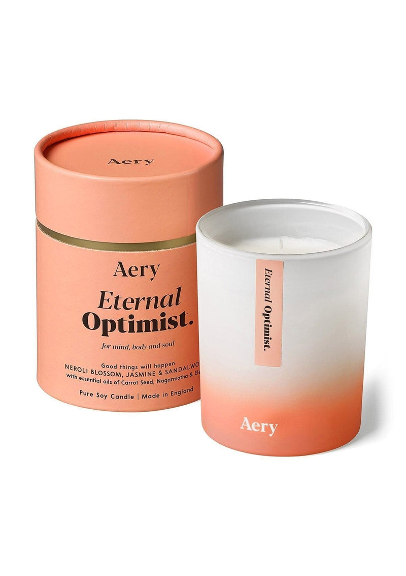 aery living eternal optimist scented candle next to orange product packaging