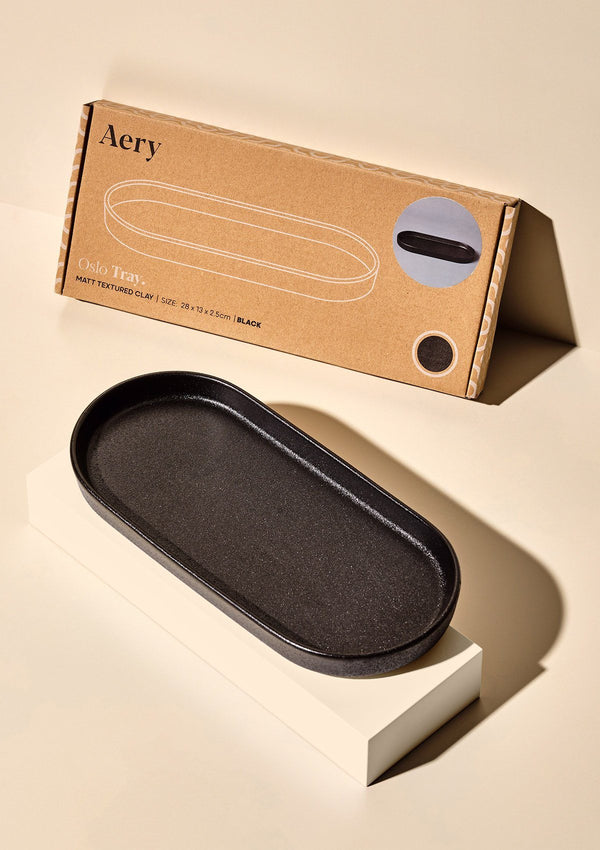 aery living textured dark grey ceramic display tray, next to kraft product packaging against a cream background