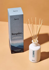 aery living inspire reed diffuser next to blue product packaging on an orange background