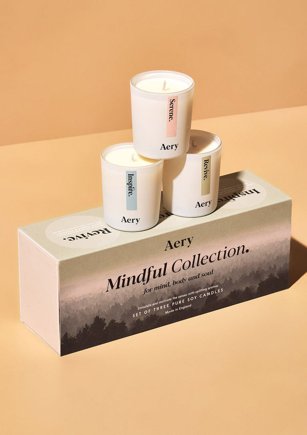 aery living mindful miniature votive candles displayed decoratively with product packaging on an orange background