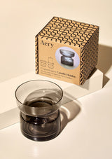 aery living smokey glass coloured tea light holder displayed next to product packaging on a cream coloured background