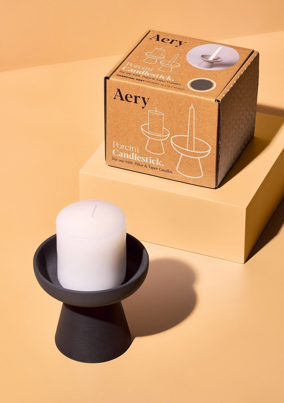 aery living charcoal grey ceramic candle holder displayed with white pillar candle and product packaging against a white backround