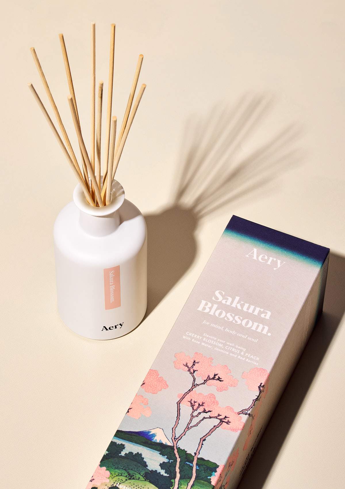 aery living sakura blossom reed diffuser next to illustrative product packaging on a cream background