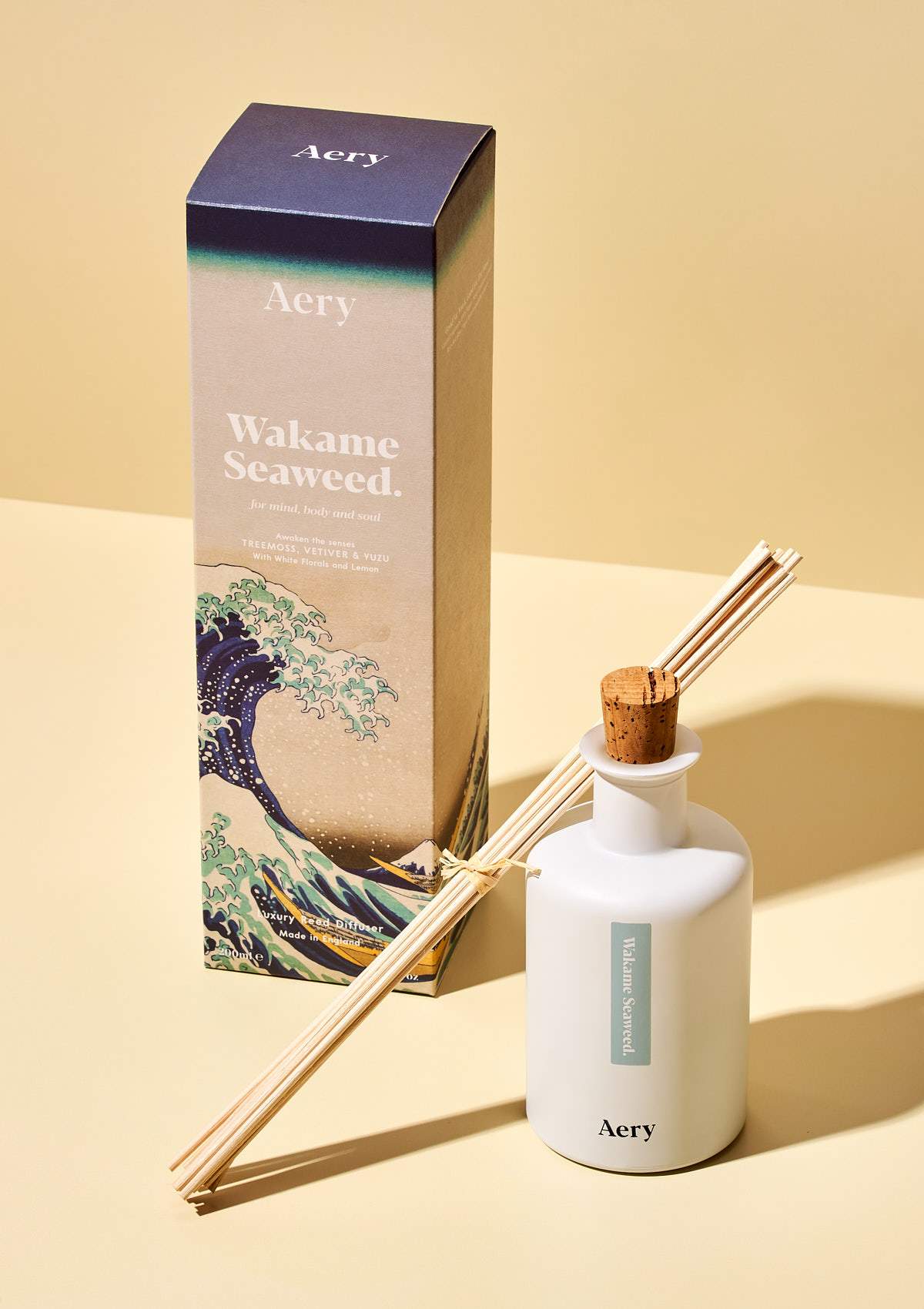 aery living wakame seaweed reed diffuser and product packaging on a yellow background